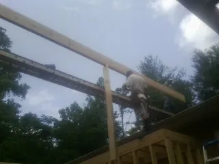 Carpenter setting a ridge beam over a new addition frame — Ice Dam Removal by Roofing Brothers in Corfu