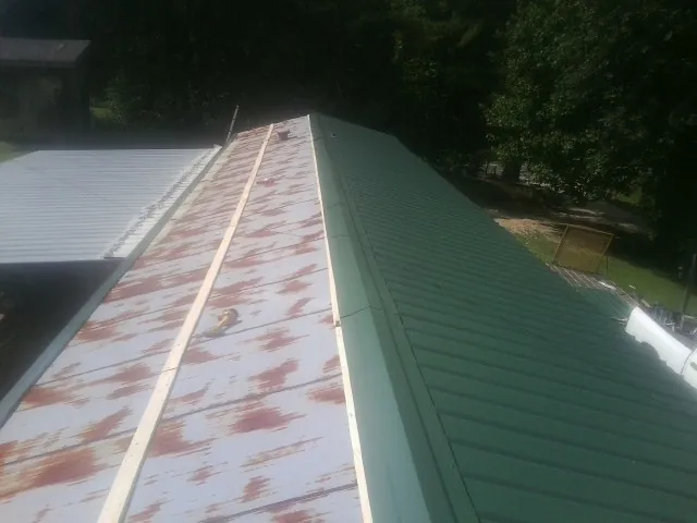 Old rusted panels beside newly installed green metal roofing — Wind Damage Roof Repair by Roofing Brothers in Corfu