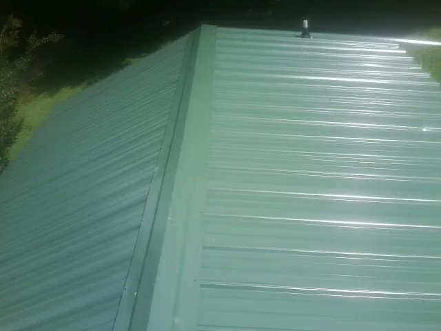 New green metal panels meeting at the ridge of a roof — Flat Roof Repair work by our crew in Corfu